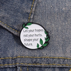 Round enamel brooch with inspirational quote pinned on blue denim fabric background