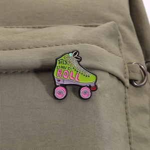 Close-up of a green roller skate enamel pin with pink wheels on an olive canvas bag
