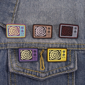 Broches en émail TV rétro avec motif en spirale présentées sur veste en jean bleue