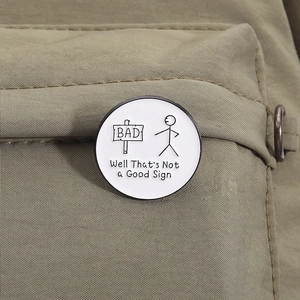 Gros plan d'un pin's en émail humoristique avec citation sur un sac à dos en toile