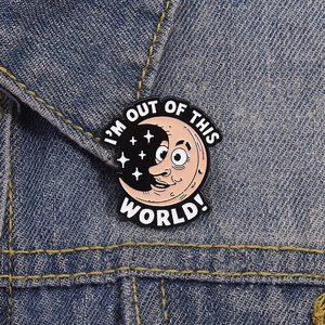 Cartoon moon enamel pin badge on denim jacket with 'I'm out of this world' text
