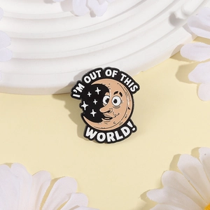 Cartoon moon enamel brooch with 'I'M OUT OF THIS WORLD' text on a decorative tray