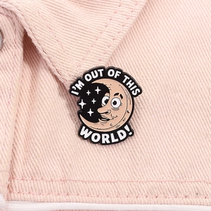Close-up of enamel moon brooch with I'M OUT OF THIS WORLD text on pink denim jacket