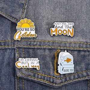Cartoon enamel pin set with golden sun and quote backpack designs on denim jacket