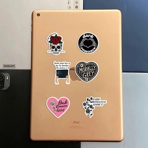 Detail of dark romance stickers with skulls and roses applied on a golden tablet surface