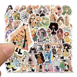 Gros plan d'une main tenant un autocollant de fille de dessin animé dessiné à la main