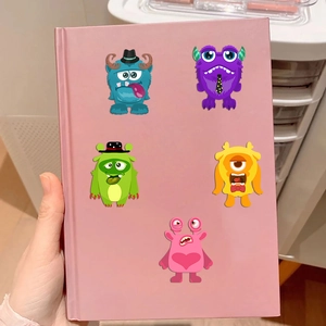 DIY cartoon monster stickers shown on a pink notebook cover for creative decoration