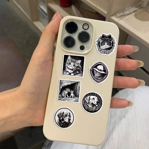 Detailed view of hand holding black and white artistic cat and dog stickers for laptop decor