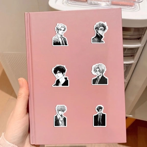 Dettaglio di adesivi anime boy in bianco e nero su una copertina di taccuino rosa
