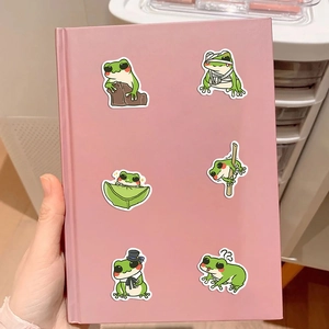 Close-up of cute cartoon frog stickers applied on a pink notebook for decoration