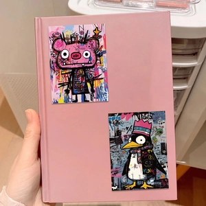Pink graffiti style notebook with artistic street art stickers featuring crown and penguin