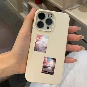 Detail of matte cream silicone phone case with scenic stickers held in a hand