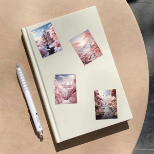 Detail view of aesthetic pink scenery stickers and white pen on a minimalist notebook