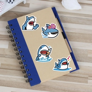 Cute cartoon shark stickers featuring various expressions on a blue coil notebook