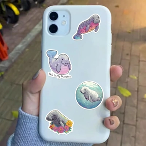 Close-up of cute cartoon manatee stickers applied on the back of a white smartphone