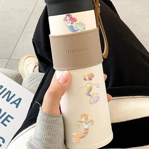 Detail of white stainless steel thermos with leather sleeve and mermaid stickers
