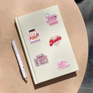 Détail d'autocollants de livres roses avec chats et citations sur un carnet