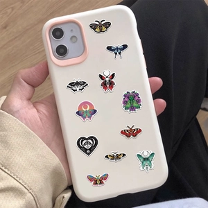Detail showing various moth and moon stickers applied on a light beige phone case