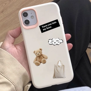 Gros plan d'un collage d'ours en peluche sur une coque iPhone blanc cassé tenue