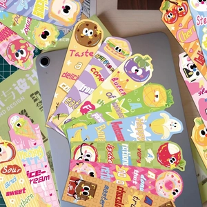 Close-up of cute cartoon food bookmarks scattered on a cutting mat and tablet surface