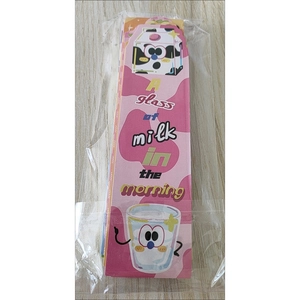 Detail view of cute cartoon milk bookmarks in transparent packaging on a wooden surface