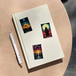 Detail of tarot stickers featuring The Hermit and Death designs on a cream notebook cover