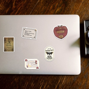 Macro shot of vintage fantasy potion stickers applied on a silver laptop surface