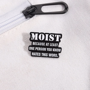 Detail of MOIST quote enamel pin on white canvas bag with clear metal texture
