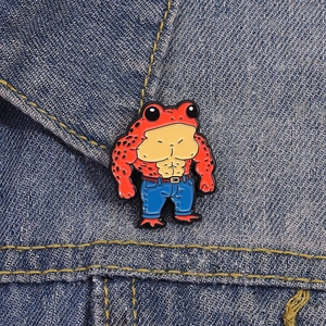 Close-up of muscular red frog enamel brooch pin with 3D muscles on denim jacket