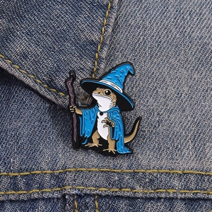 Detailed view of wizard lizard enamel pin attached to blue denim fabric texture