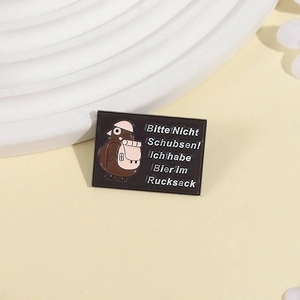 Detail of black enamel pin with cartoon pigeon and German text on beer theme
