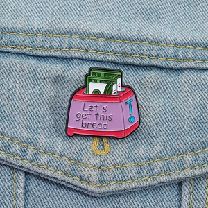Close-up of bread maker enamel pin with 'Let's get this bread' text on denim jacket