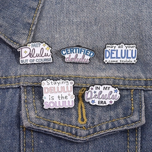Lot de cinq épingles et broches en émail Delulu stylisées sur une veste en jean