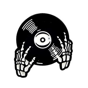Macro detail of enamel punk brooch featuring vinyl record and skeleton hand design