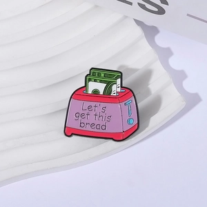 Detail of pink toaster enamel pin with 'Let's get this bread' text and green bills