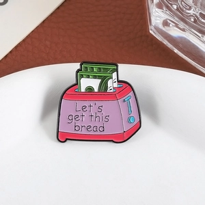 Detailed close-up of a purple toaster enamel pin on a white plate with text Let's get this bread