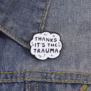 Détail d'un pin's émaillé en forme de nuage avec citation sur tissu denim et étoiles