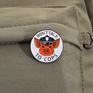 Cartoon pig sheriff enamel pin with Don't Talk To Cops text on green canvas background