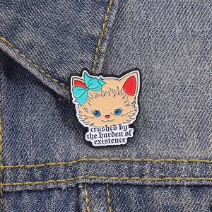 Broche chat en émail avec nœud bleu et texte sur le col d'une veste en jean