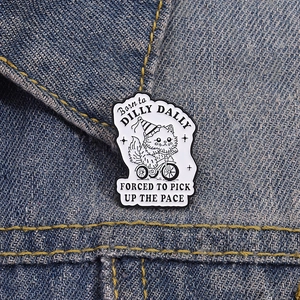 Detail of cartoon cat on tricycle enamel pin fixed on blue denim jacket fabric