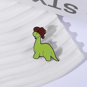 Mignonne épingle en émail de dinosaure vert avec chapeau de cowboy sur plateau blanc