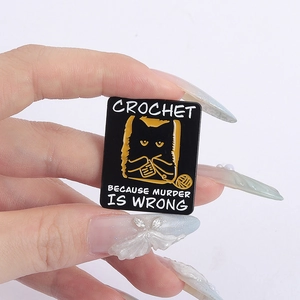 Black cat crochet enamel pin with Crochet Because Murder Is Wrong slogan on hand
