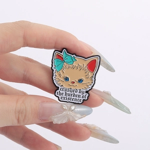 Light brown cat enamel pin with blue bow featuring artistic quote on a white background