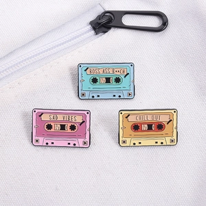 Set mit drei bunten Retro-Kassetten-Emaille-Pins auf einer weißen Stofftasche