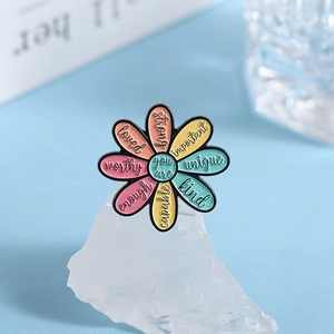 Colorful floral enamel pin with rainbow petals and inspirational words on blue background