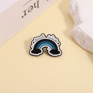 Détail d'un pin's émaillé arc-en-ciel 'dead inside' sur un fond de style minimaliste