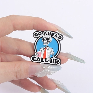 Detail of funny skeleton employee enamel pin with Go Ahead and Call HR slogans