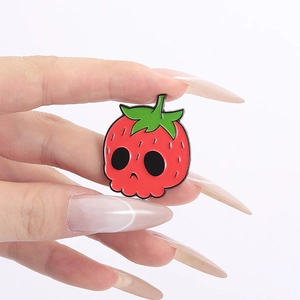 Close-up of cute strawberry skull enamel pin in red zinc alloy with detailed leaf top