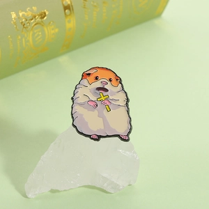 Macro shot of cute cartoon hamster enamel pin with yellow cross on textured stone
