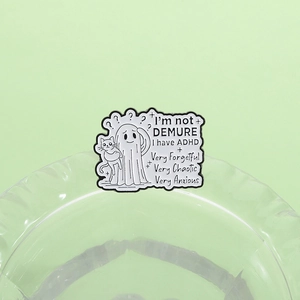 Detail shot of a ghost cat enamel pin with ADHD text on a transparent glass edge